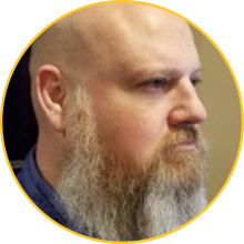The side profile of a bald man with a gray beard and fair skin